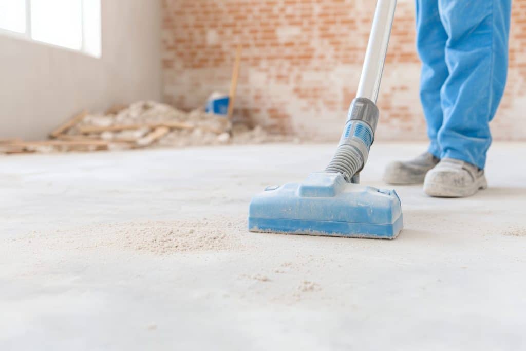 A worker cleaning a floor with a vacuum demonstrating cleanliness and attention to detail in a construction site